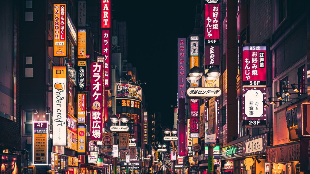 Calle de Tokio por la noche con carteles luminosos.