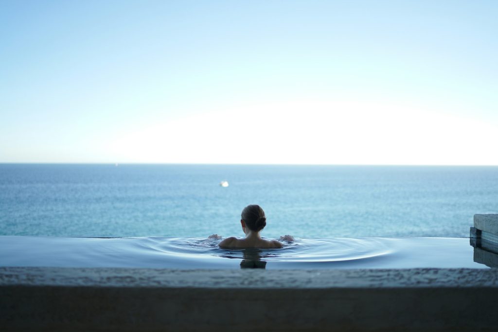 Mujer disfrutando de una piscina infinita con vista al océano