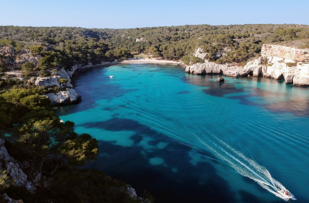 Vista aérea de Cala Macarelleta con aguas turquesas y acantilados en Menorca.