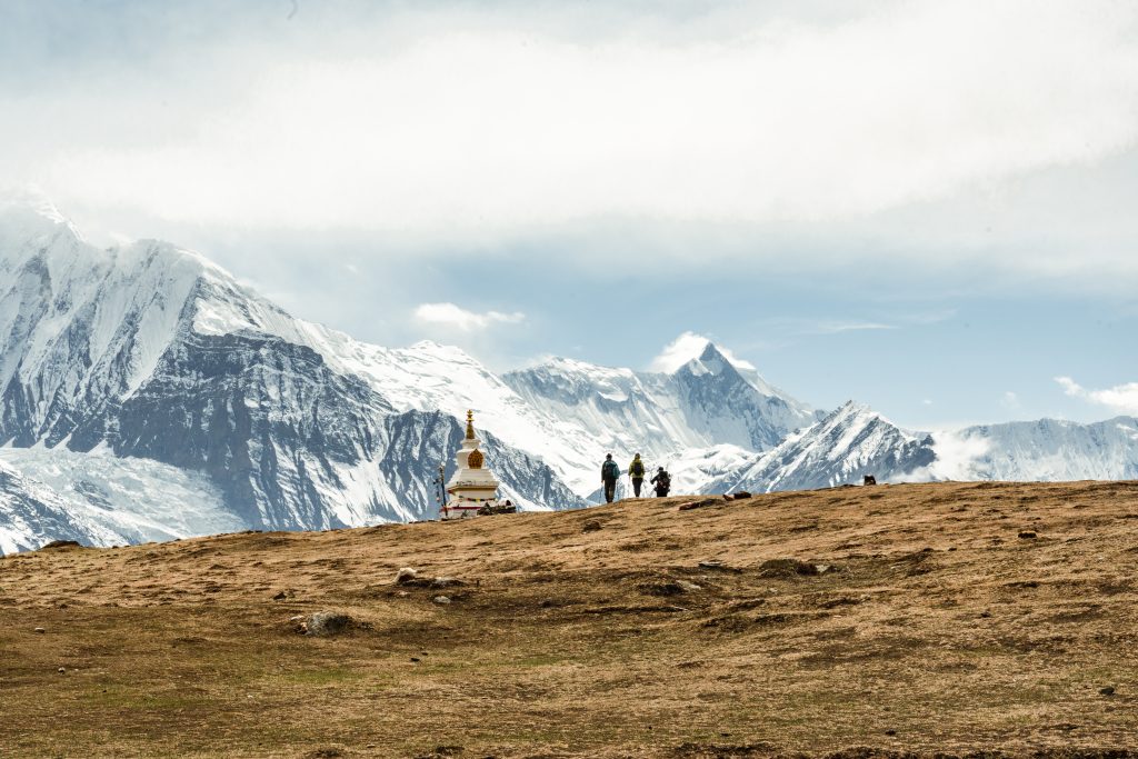 Paisaje del Himalaya en Nepal con montañas nevadas y excursionistas durante un trekking de alta montaña.