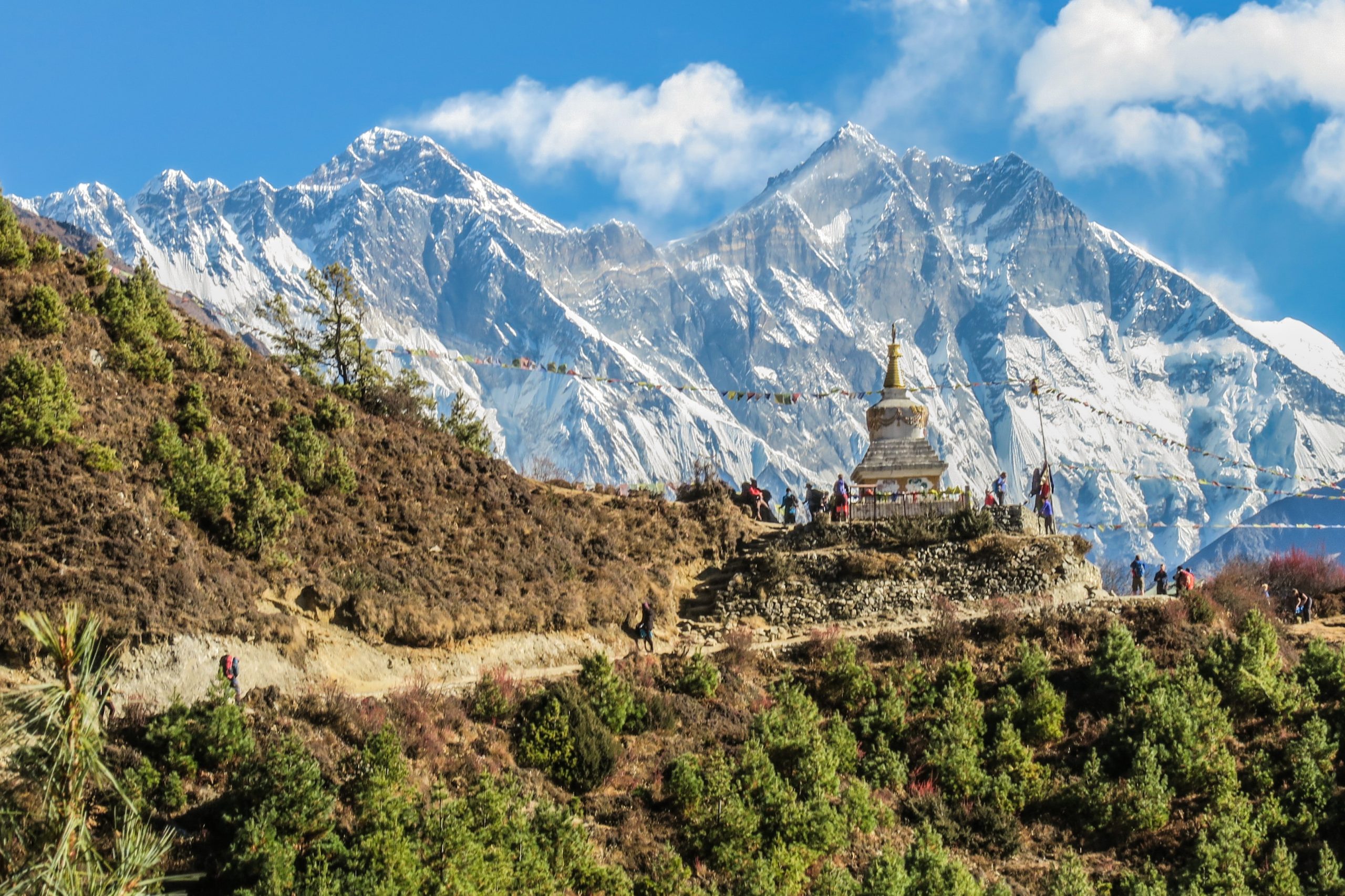 Estupa budista durante una ruta de trekking en el Himalaya con montañas nevadas de Nepal al fondo.