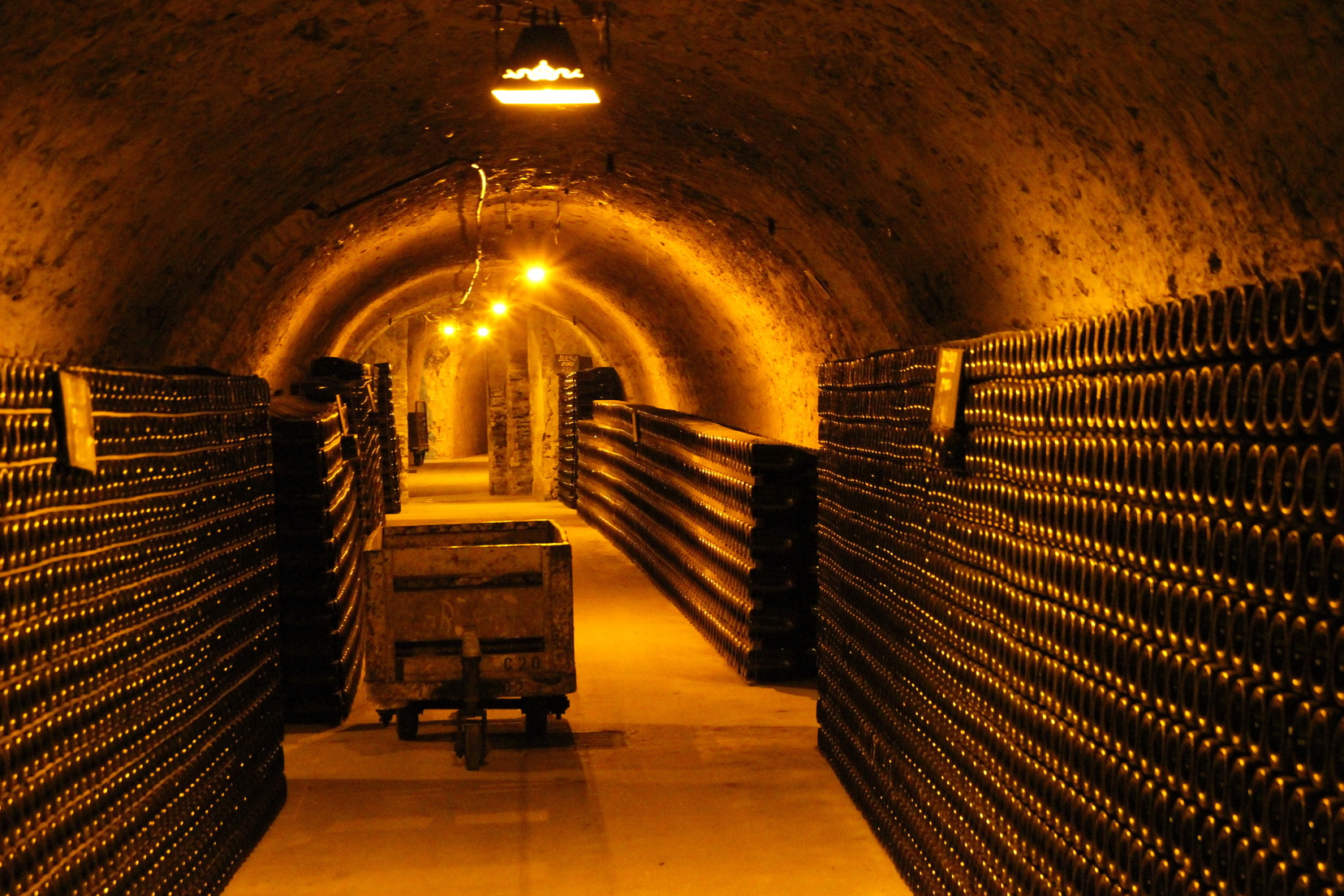 Pasadizo subterráneo de cavas de champagne con vagoneta minera y rimas de botellasPasadizo subterráneo de cavas de champagne con vagoneta minera y rimas de botellas